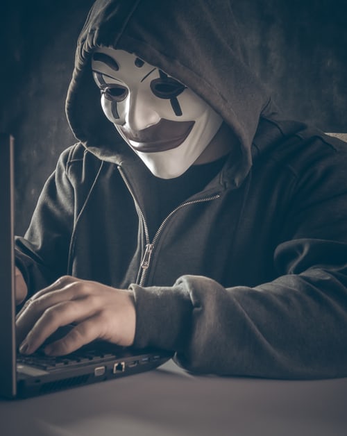 A man with a mask haking a computer